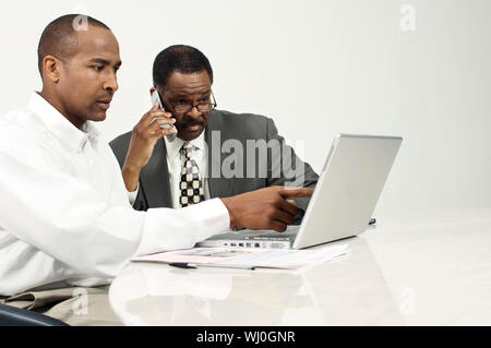 Portrait à l'écran de l'ordinateur portable avec collègue on call at desk in office Banque D'Images