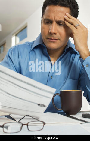 Tendu mature businessman reading document at desk in office Banque D'Images