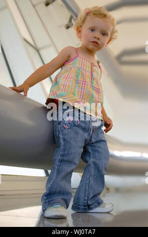 Un blondie girl debout à côté d'un grand tube de métal à l'ensemble industriel. Regardant la caméra à partir de la vue de dessous. Banque D'Images