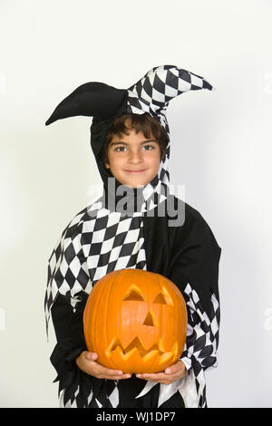 Cute Hispanic boy in jester outfit holding pumpkin isolé sur fond blanc Banque D'Images