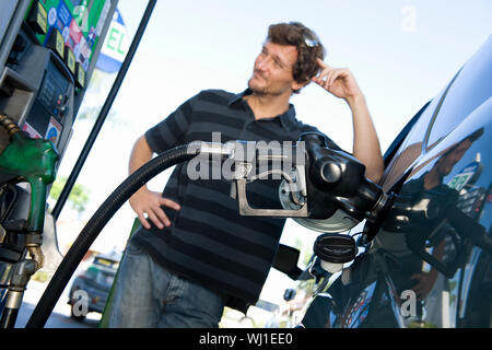 Blurred smiling man refueling car à la station de gaz naturel Banque D'Images