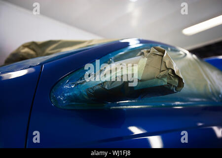 Gros plan du projecteur endommagé d'une voiture bleue Banque D'Images