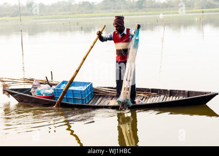 Kerala, Inde, le 10 janvier 2018 - un pêcheur local pêcher avec son filet de pêche sur un bateau d'aviron lors d'une zone de remous Kerala au coucher du soleil au crépuscule. Banque D'Images