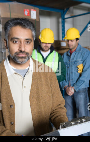 Portrait d'un homme sérieux avec des collègues dans l'arrière-plan à l'usine Banque D'Images