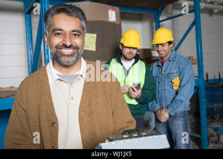 Portrait of a smiling man avec des collègues dans l'arrière-plan à l'usine Banque D'Images