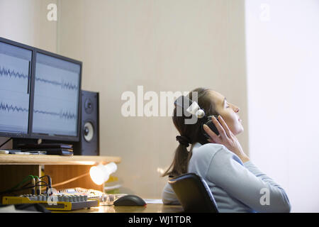 Vue latérale d'une femme ingénieur du son à écouter de la musique Banque D'Images