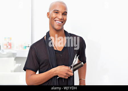 Portrait of happy homme styliste holding hairbrush et ciseaux Banque D'Images