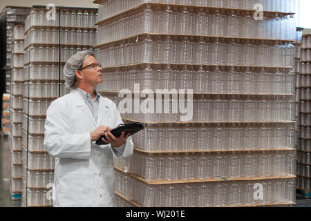L'homme l'inspection de l'eau en bouteille dans l'entrepôt de distribution Banque D'Images