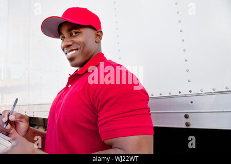 Portrait d'un jeune homme avec des camions de livraison en arrière-plan Banque D'Images