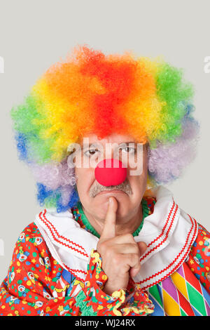 Portrait de senior homme en colère clown avec le doigt sur le menton sur fond gris clair Banque D'Images