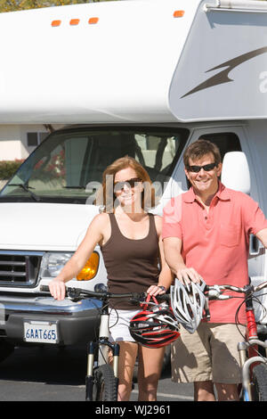 Portrait of happy Young couple standing avec des vélos contre caravan Banque D'Images