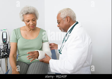 Senior male doctor checking patients main fracturée en clinique Banque D'Images