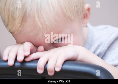 Closeup portrait of shy baby boy peeking sur président sur fond de couleur Banque D'Images