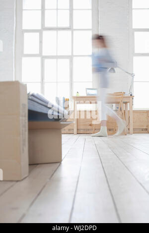 Blurred motion de femme marche avec l'accent sur carton dans loft Appartement Banque D'Images