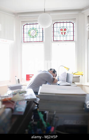 Fatigué businessman sleeping at desk in creative office space Banque D'Images