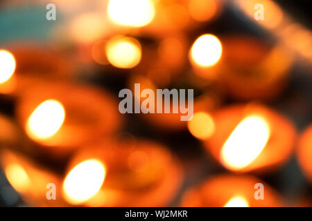 Gros plans flous, à l'allumage de diyas à la main ou d'une bougie pour le festival hindou de Diwali. Ces pots colorés earthern tenir l'huile et un cotto Banque D'Images