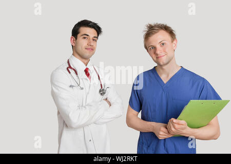 Portrait of doctor standing with coworker sur fond gris clair Banque D'Images