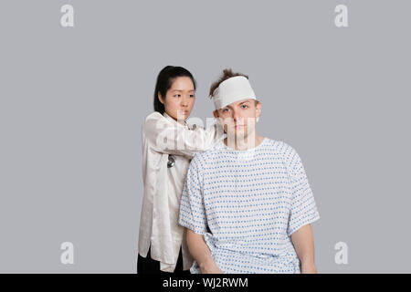 Femme médecin s'habiller tête du patient avec bandage Banque D'Images