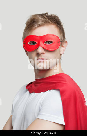 Portrait of young man wearing superhero costume contre l'arrière-plan gris Banque D'Images