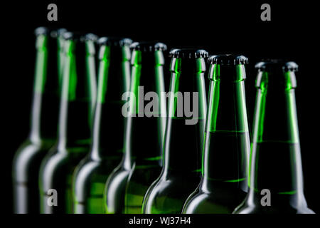 Rangée de bouteilles en verre de bière sur fond sombre Banque D'Images