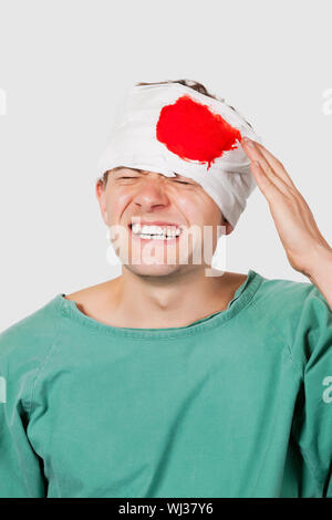 Young male patient avec des blessures graves à la tête contre l'arrière-plan gris Banque D'Images