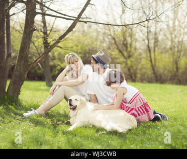 Family sitting in park with dog Banque D'Images