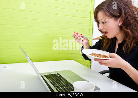 Close up of woman eating at her desk Banque D'Images