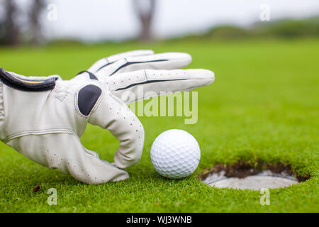 Close-up of a man's hand putting balle de golf dans le trou en cours Banque D'Images