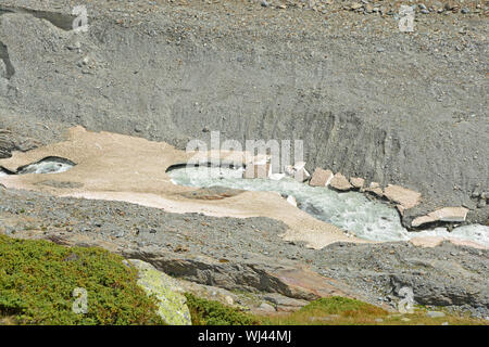 Un glacier stream traverse vieux ponts de neige dans les montagnes. Les pièces en haut à gauche du glacier peut être vu Banque D'Images