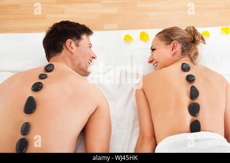 Couple un massage aux pierres chaudes dans un spa où des pierres chauffées sont placées le long de la colonne vertébrale pour détendre les muscles Banque D'Images
