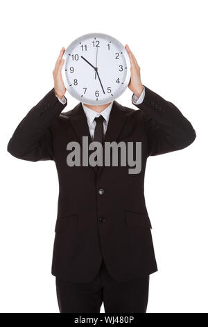 Businessman holding réveil sur le visage. Isolated on white Banque D'Images