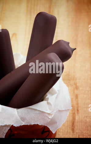 Tas de bâtonnets de crème glacée dans le chocolat noir glacé sur fond de bois rustique Banque D'Images