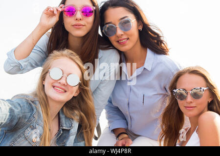 Portrait de quatre belles jeunes fille étudiante à lunettes colorés sur le fond du ciel Banque D'Images