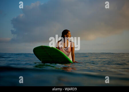 Surfer sur l'attente des femmes de l'océan en surfboard Banque D'Images