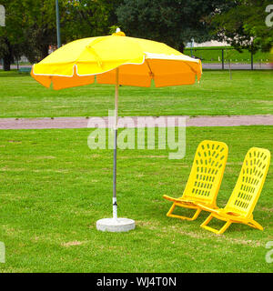 Des chaises longues et des parasols jaunes debout sur l'herbe Banque D'Images