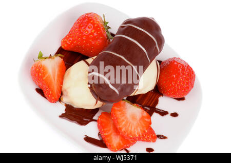 Arrangement des éclairs au Chocolat glacé avec sauce au chocolat et fraises tranchées gros plan sur plaque blanche. Vue d'en haut Banque D'Images
