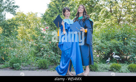 Un groupe de jeunes femmes diplômées. Female graduate smiling est contre l'arrière-plan de diplômés universitaires. Concept de l'éducation, l'obtention du diplôme et kno Banque D'Images