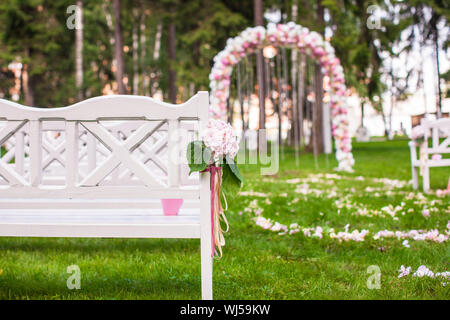 Des bancs et des fleurs de mariage arch pour une cérémonie de mariage en plein air Banque D'Images