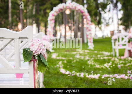 Des bancs et des fleurs de mariage arch pour une cérémonie de mariage en plein air Banque D'Images