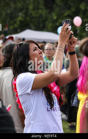 Jeune femme à prendre des photos avec un téléphone mobile à Helsinki Pride 2019 after-party dans le parc Kaivopuisto Banque D'Images