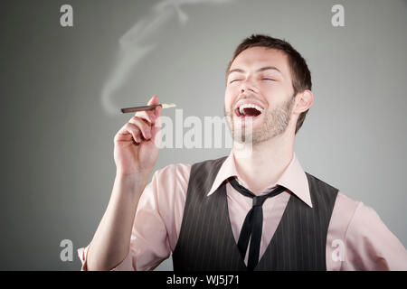 Portrait of laughing young Caucasian man with petit cigare Banque D'Images