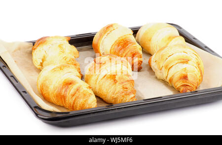 Des croissants frais sur Four noir avec du papier parchemin isolé sur fond blanc Banque D'Images