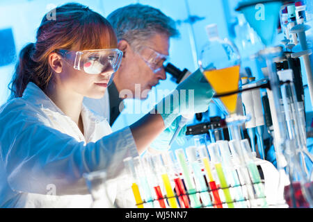 Young female scientist et son superviseur et de pipetage microscoping dans le laboratoire de recherche en sciences de la vie (biochimie, gen Banque D'Images