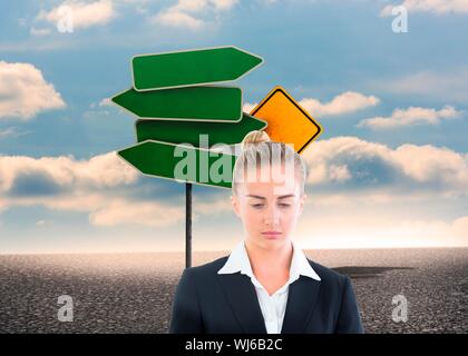 Image composite de blond businesswoman looking thoughtful en face de la signalisation routière Banque D'Images