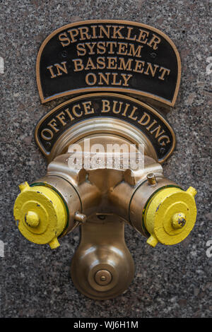 New York, NY, USA - Décembre 2018 - Golden et jaune-fontaine ancienne tuyau vertical et système de gicleurs en sous-sol connexion hors d'un bâtiment Banque D'Images