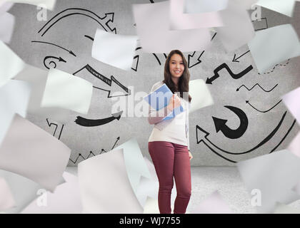 Image composite de l'élève debout dans une salle informatique et la tenue d'un dossier tout en souriant Banque D'Images