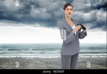 Composite image of businesswoman posing with binoculars Banque D'Images