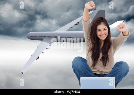 Image composite d'une femme célèbre en face de son ordinateur portable comme elle sourit à l'avant. Banque D'Images