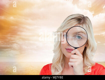 Image composite de fair-haired woman à travers une loupe sur un fond blanc. Banque D'Images