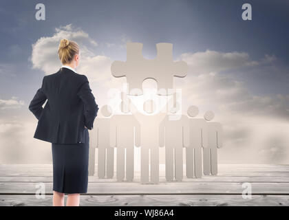 Image composite de blond businesswoman standing with hands on hips Banque D'Images